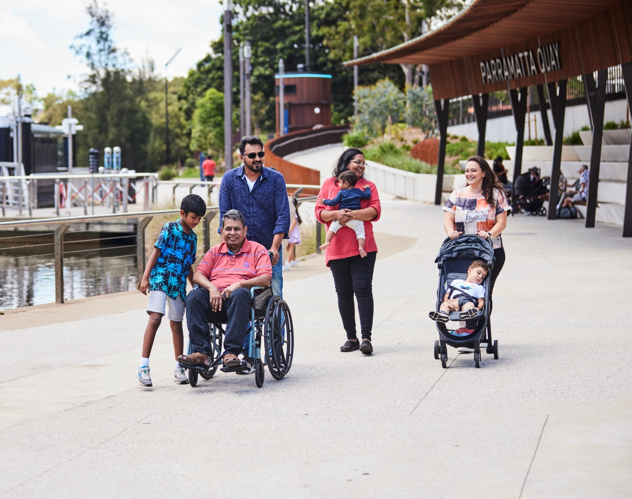 Group of people walking along side Parramatta Quay, man in wheelchair