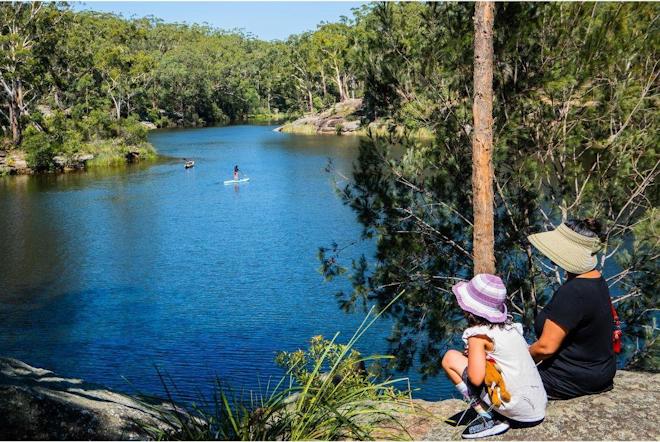 Woman and child sitting on a rock looking at Lake Parramatta