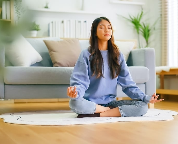 Woman sitting down in living room meditating