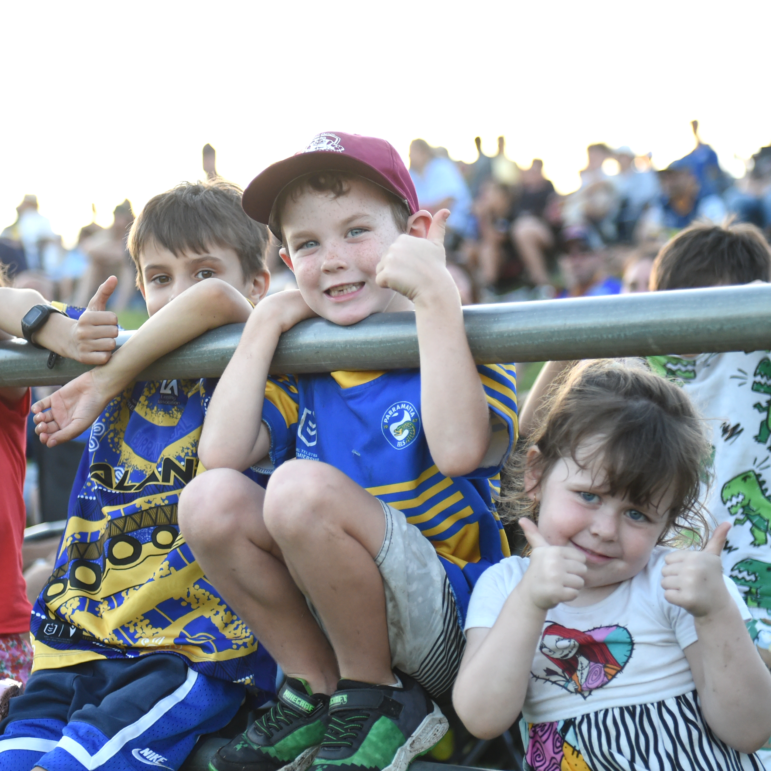 Three little children with thumbs up, two wearing Parramatta Eels jerseys