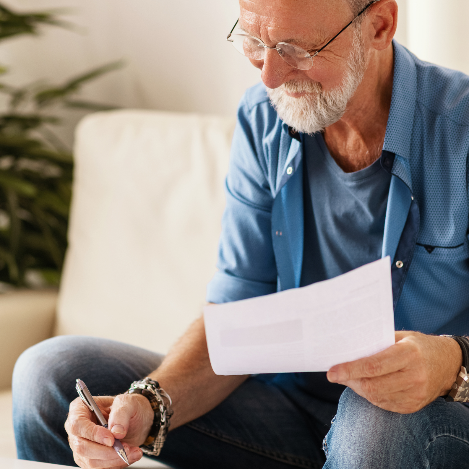 Man in blue shirt, holding piece of paper and pen