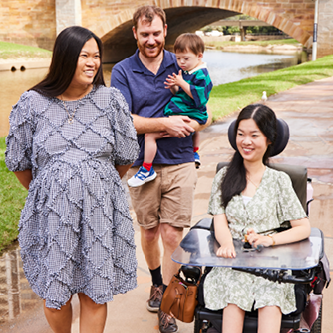 Man holding little boy, woman in blue dress and woman in wheelchair on Parramatta River path