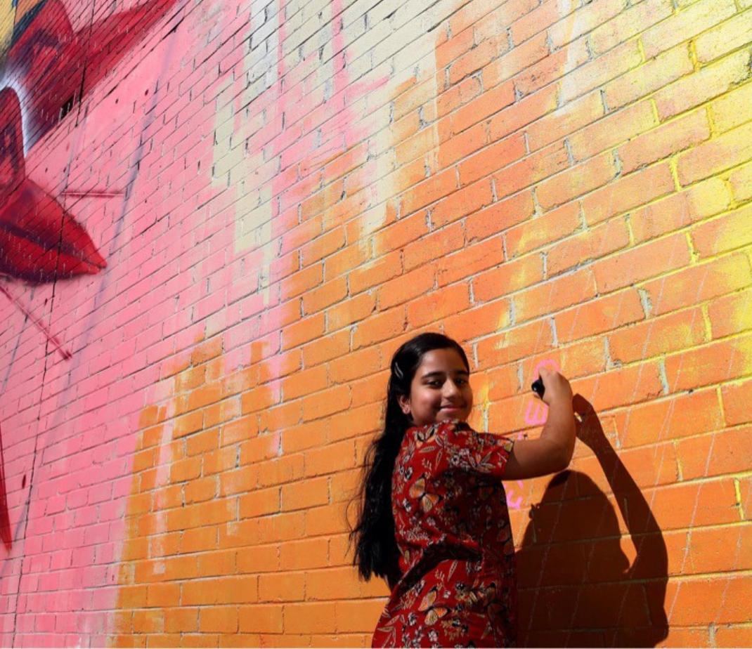 Woman paints mural on wall