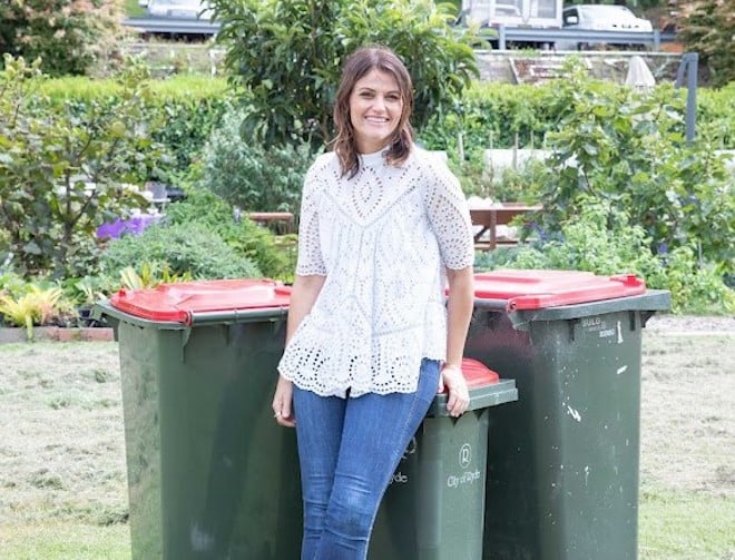 Woman standing in front of red lid bins