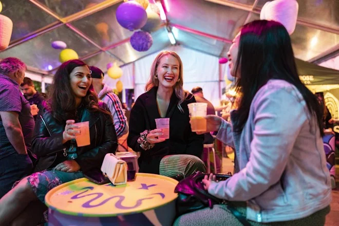 Three women having a drink at a night-time event in Parramatta